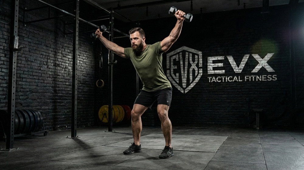 Man swinging dumbbells overhead during a conditioning set in the EVX gym